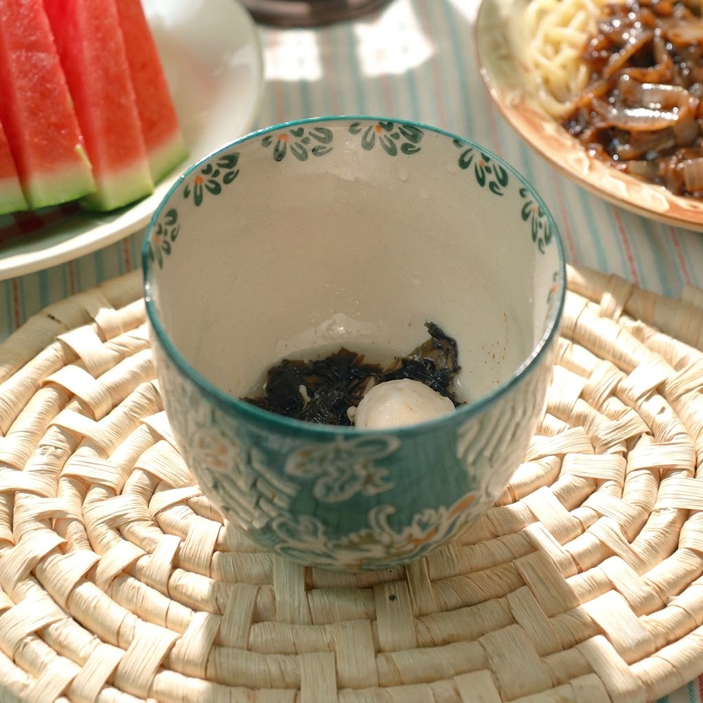 Una polpetta di maiale cotta e alga allinterno di una ciotola da zuppa in ceramica decorata.