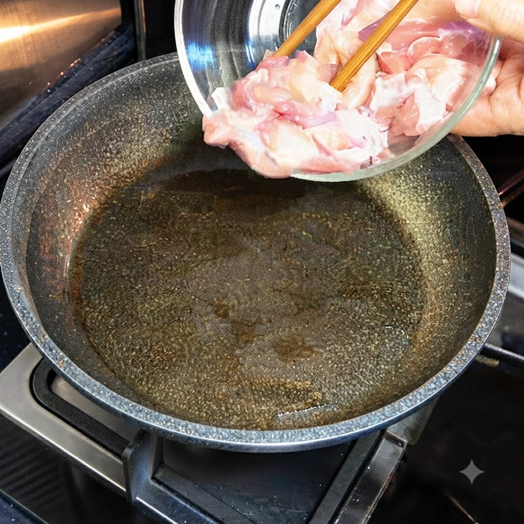 Pezzi di pollo crudo versati da una ciotola di vetro in una padella calda e unta dolio.