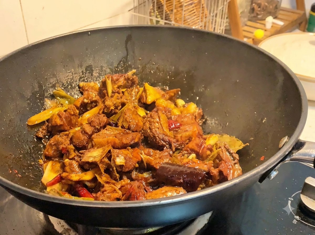 Pezzi di anatra brasata in cottura in un wok a fuoco alto mentre la salsa si riduce e si addensa.