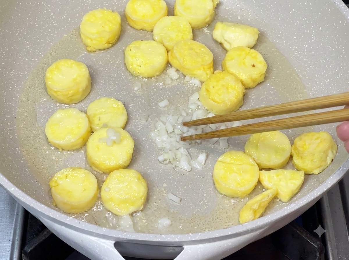 Cipollotti tritati fatti saltare in padella dopo aver rimosso lolio in eccesso per sviluppare un sapore aromatico.