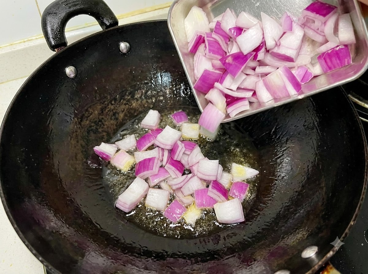 Cipolle rosse a cubetti che sfrigolano e vengono saltate in un wok nero oliato.