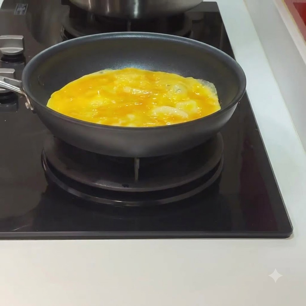 Un uovo che cuoce e inizia a rapprendersi allinterno di una padella nera su un piano cottura.