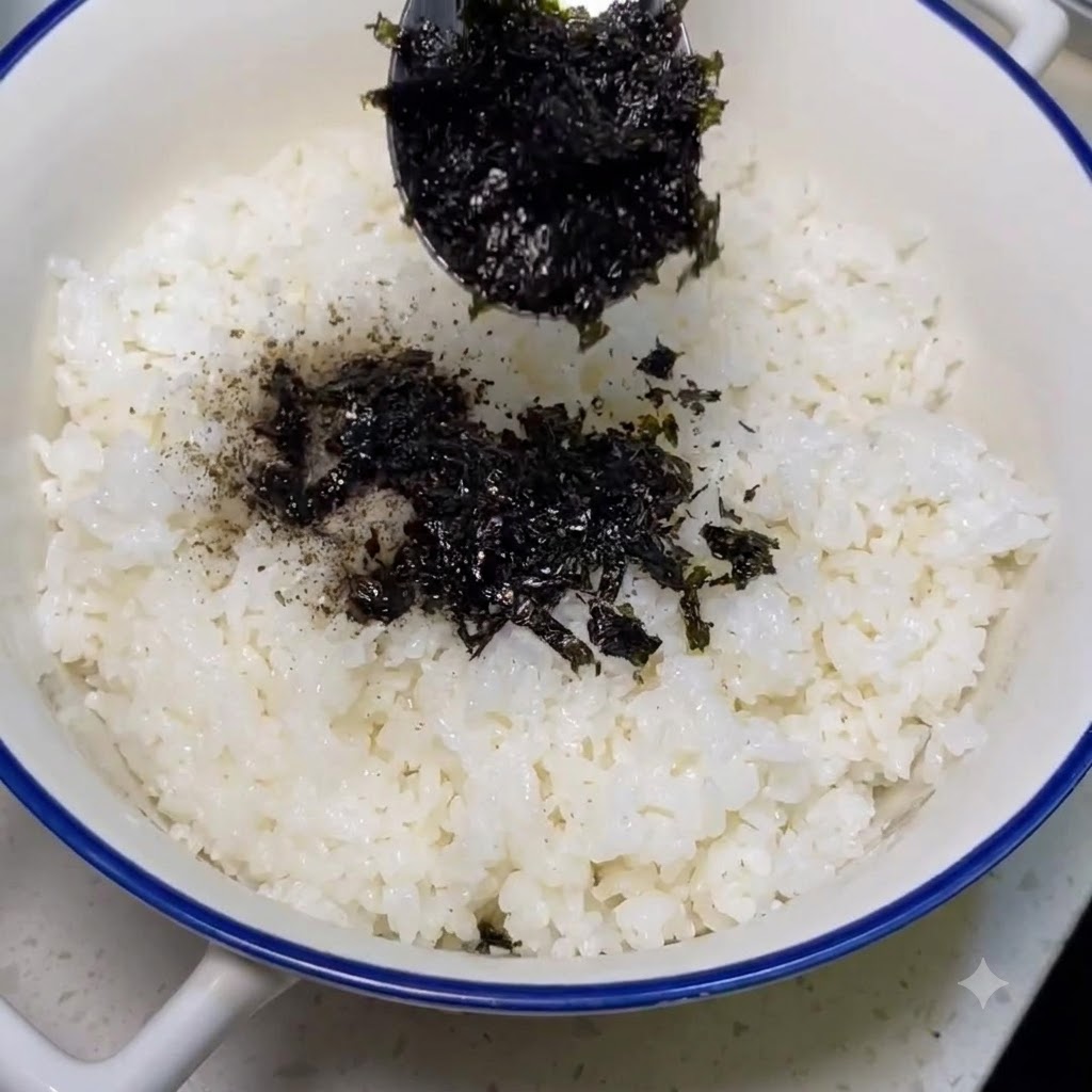 Polvere di alga cosparsa con un cucchiaio sopra il riso bianco cotto.