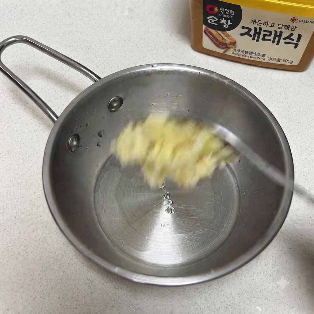 Aglio tritato e semi di sesamo aggiunti a una piccola padella in acciaio inossidabile.