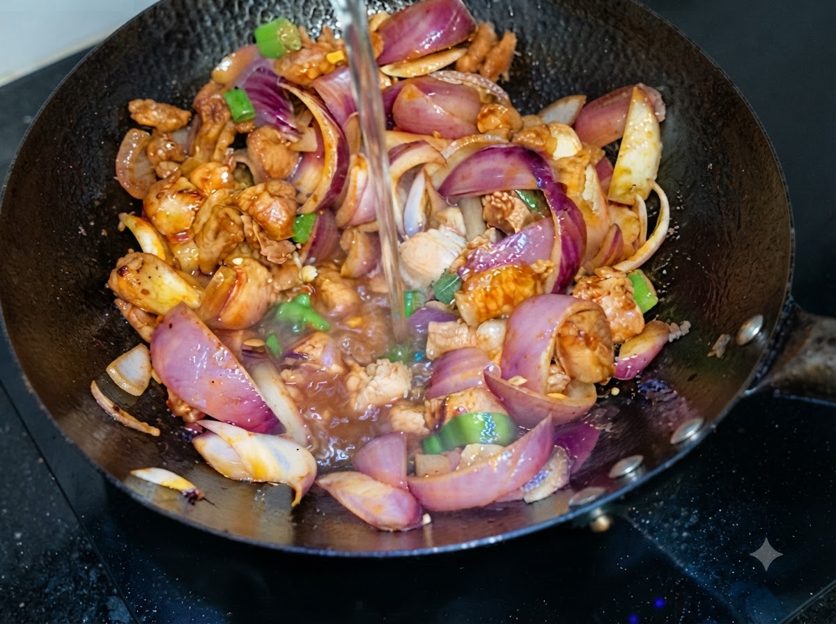 Acqua versata dallalto in un wok contenente pancetta di maiale saltata e fette di cipolla viola.