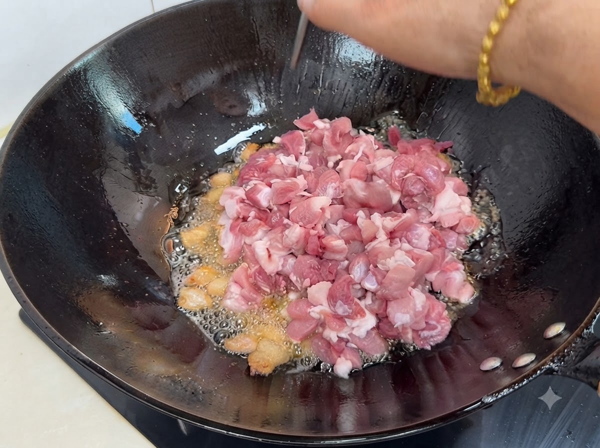Pezzi di maiale magro tagliati a cubetti freschi aggiunti nel wok caldo con grasso sciolto e spezie.