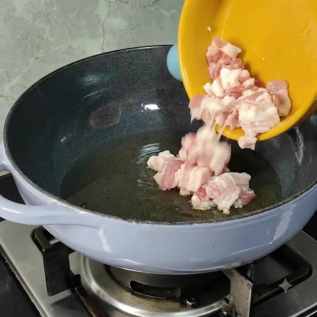 Pezzi di pancetta di maiale cruda tagliata a dadini che scivolano da una ciotola gialla in una padella riscaldata con olio da cucina.