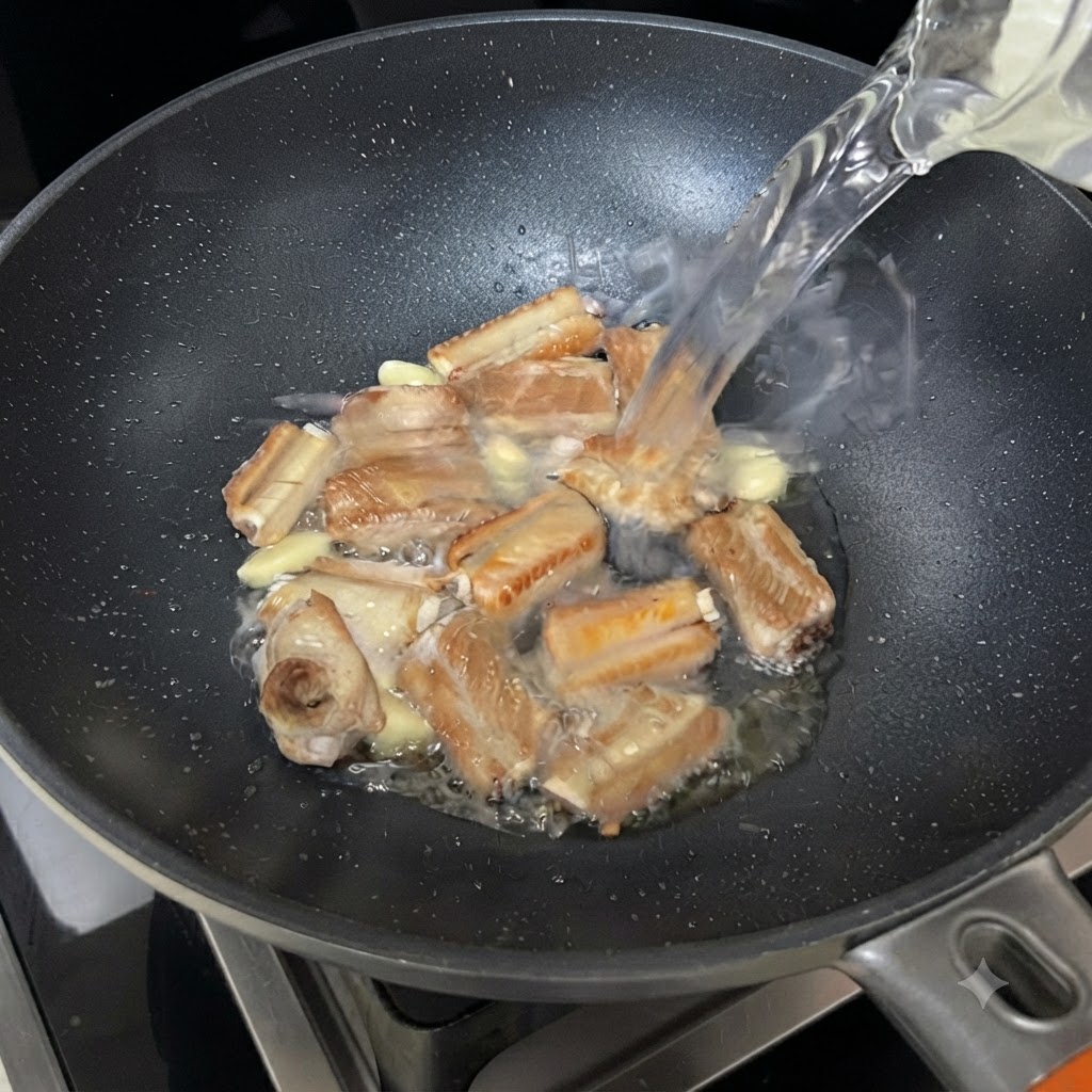 Acqua che scorre da una ciotola nella padella con le costine e laglio che sfrigolano.