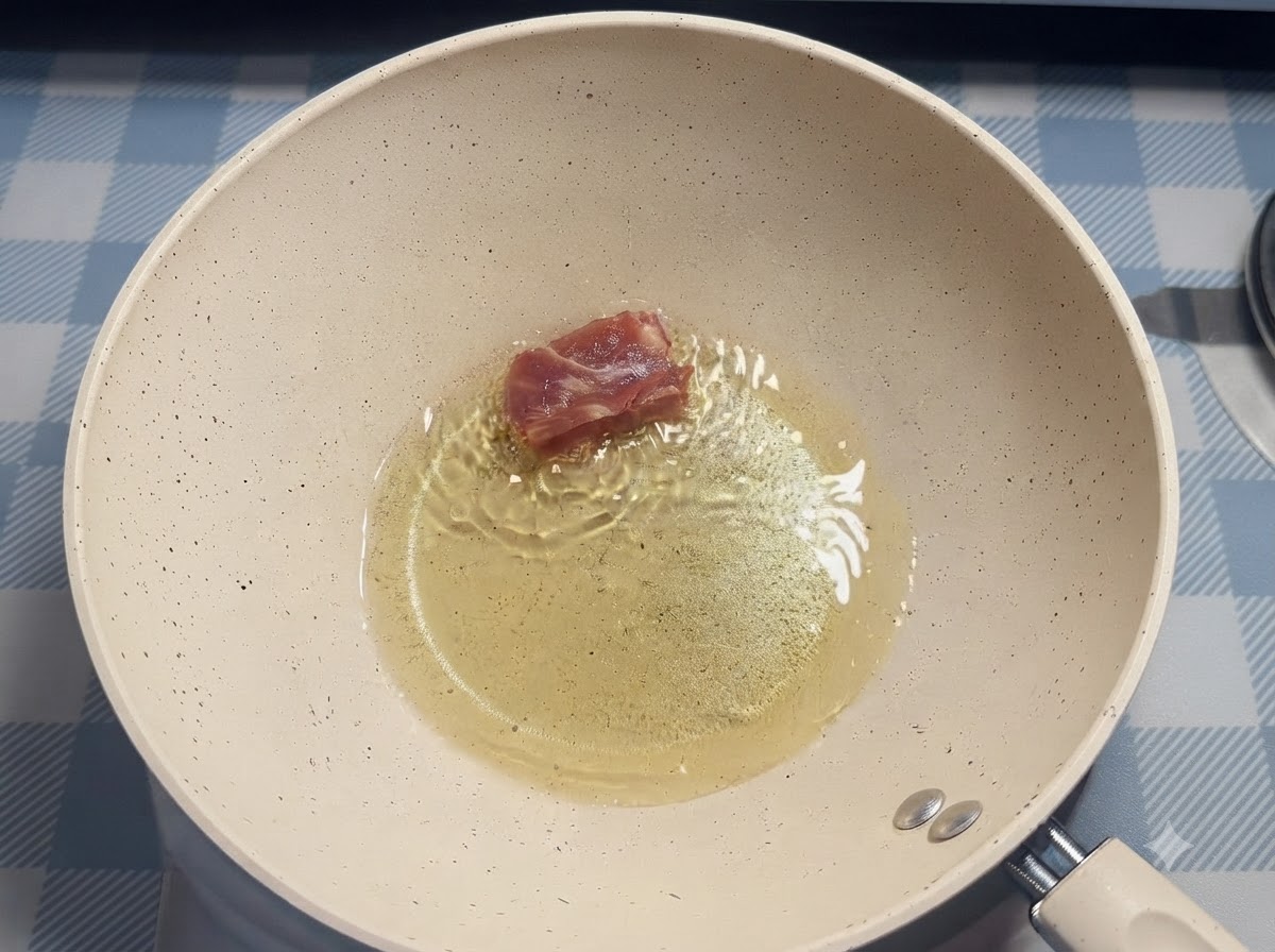 Un singolo pezzo di costina di maiale inserito nellolio caldo allinterno di una padella bianca usando le bacchette.