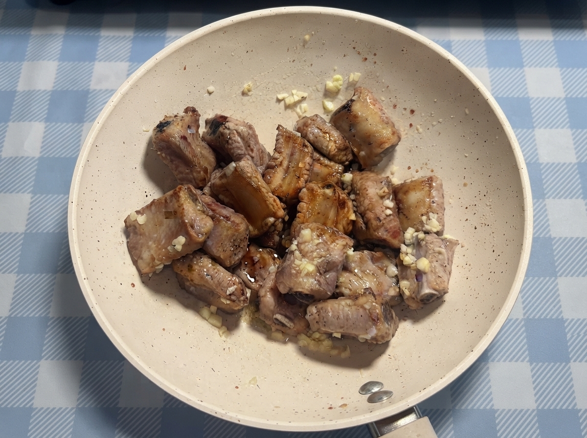 Costine di maiale condite con salsa e miele in padella prima di essere mescolate unultima volta.