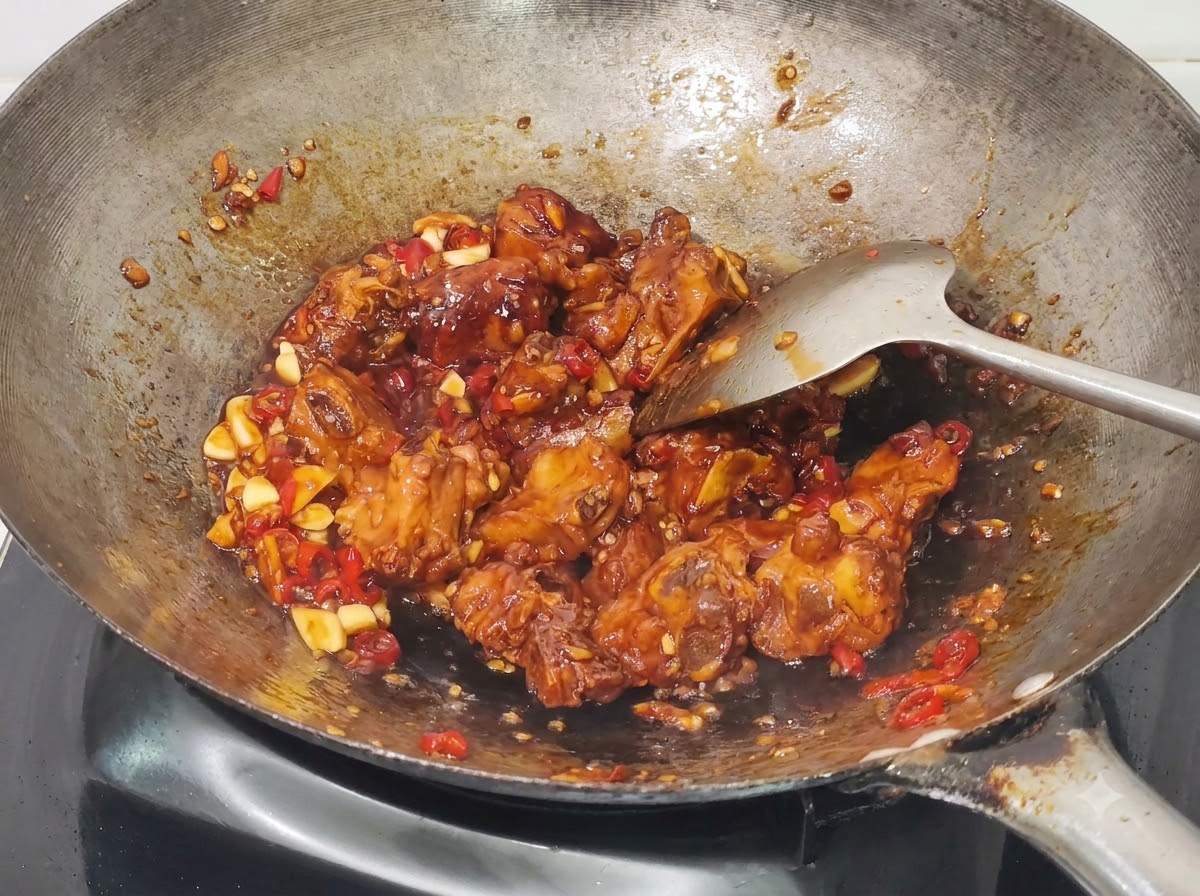 Cipollotti tritati mescolati alle costine di maiale al miele e aglio cotte nel wok.