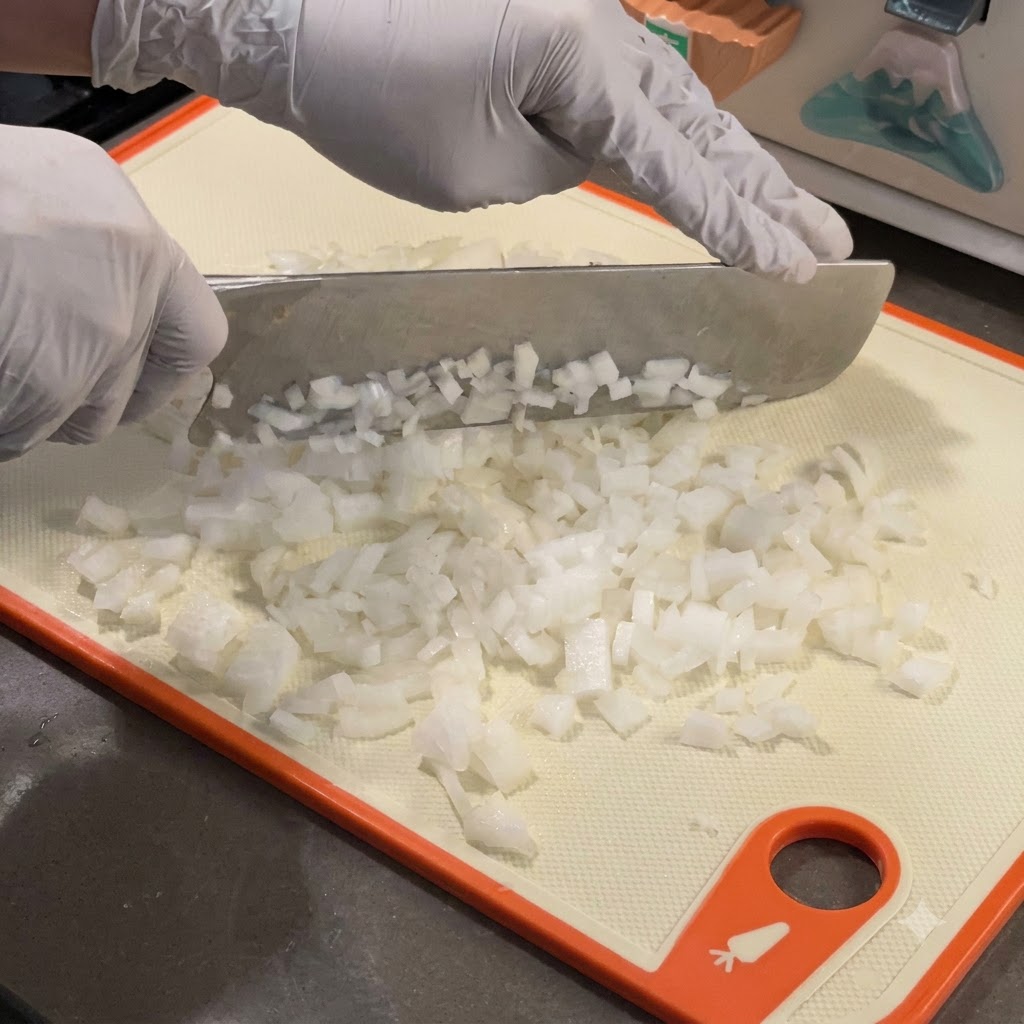 Cipolle bianche finemente tagliate a dadini che cuociono in una padella di ghisa calda.