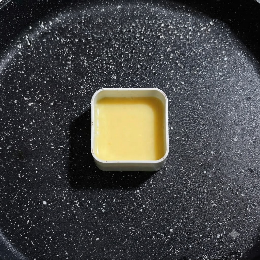 Uno stampo quadrato in metallo riempito con liquido duovo giallo adagiato nella padella di cottura, pronto per il posizionamento degli ingredienti.