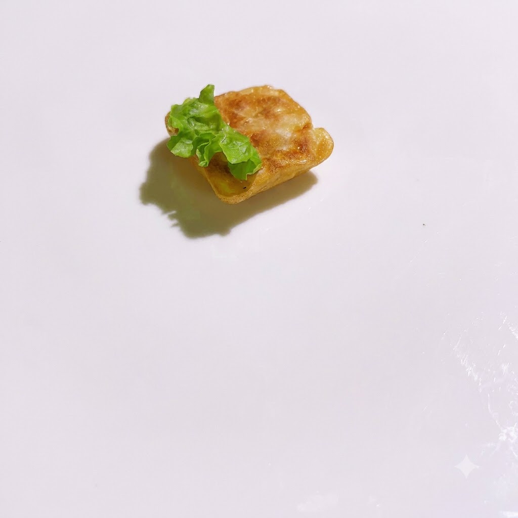 Pezzi di lattuga verde fresca disposti attorno a una base quadrata cotta su un piatto bianco.