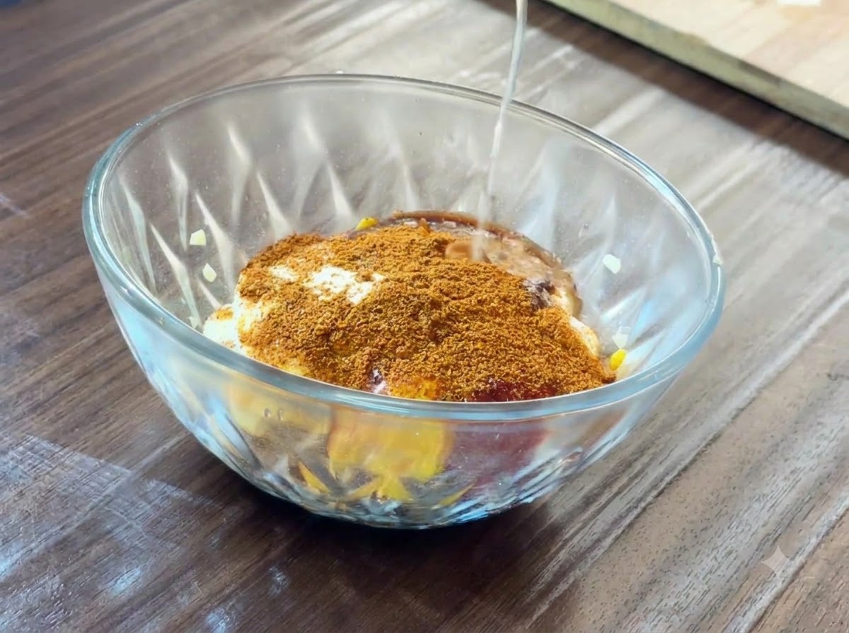 Succo di limone fresco versato da mezzo limone in una ciotola di vetro piena di vari ingredienti per salse.