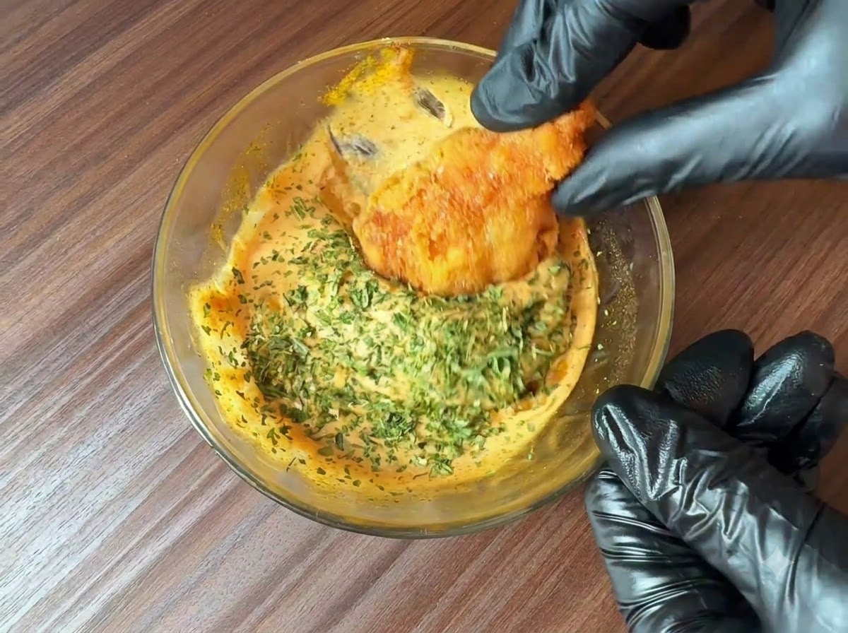 Prezzemolo fresco tritato cosparso su una ciotola di salsa per burger preparata mentre un pezzo di cibo fritto vi viene immerso.