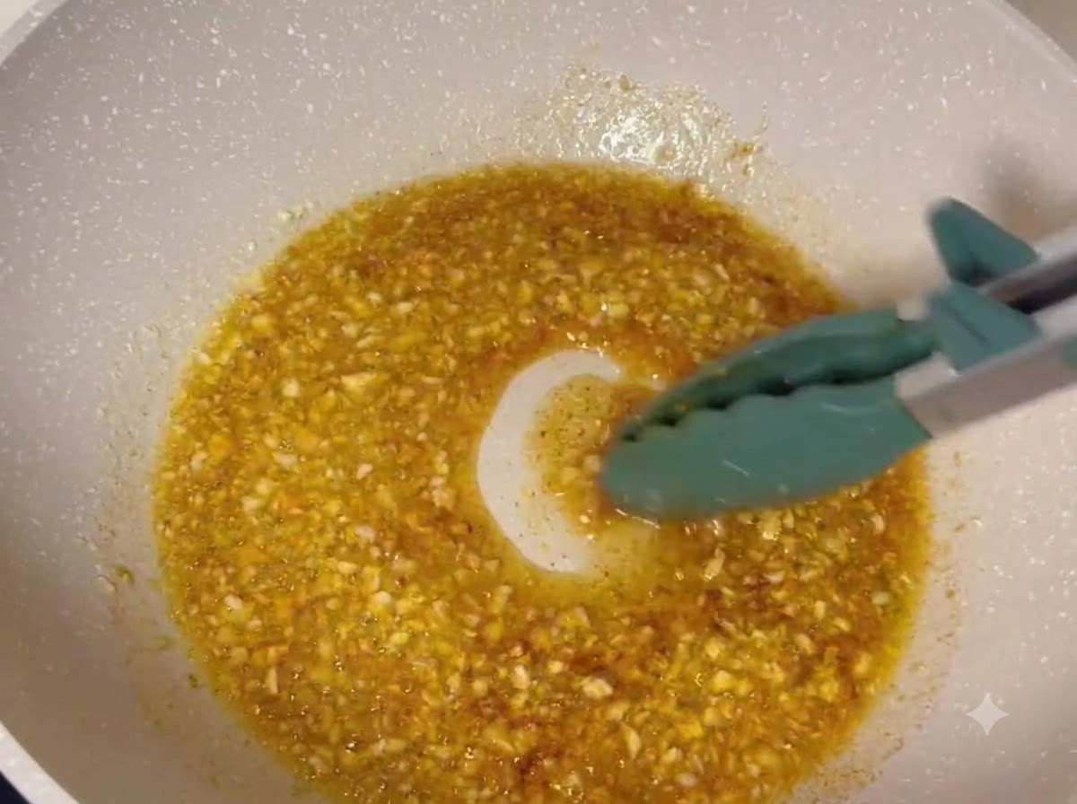 Cosce di pollo fritte saltate in una glassa di burro e aglio in ebollizione allinterno di una padella.