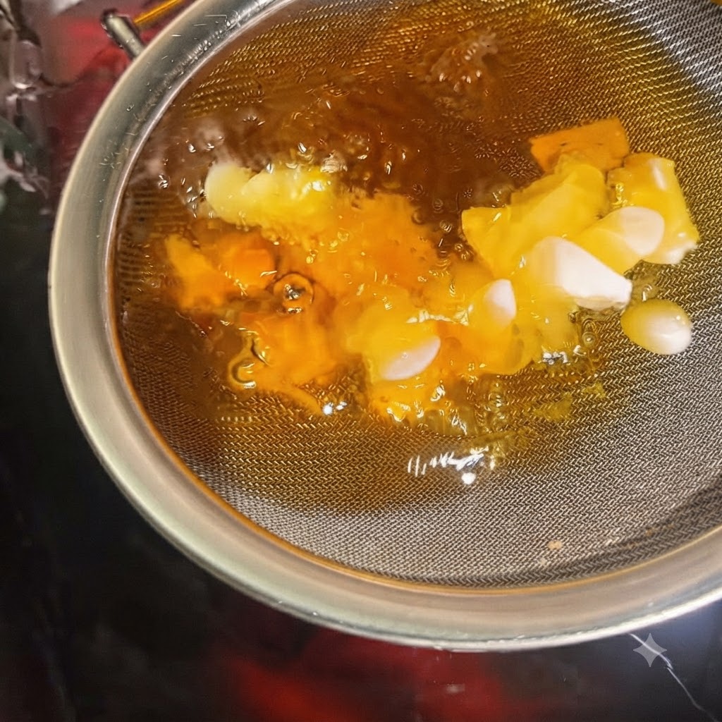 Fette daglio che diventano croccanti e dorate allinterno di un colino immerso nellolio bollente.
